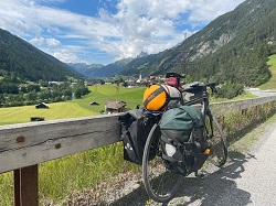 Fahrrad mit Packtaschen lehnt am Straßenrand in ländlicher Umgebung