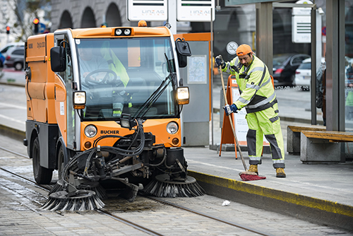 Foto: Kehrmaschine und Arbeiter mit Besen an Haltestalle