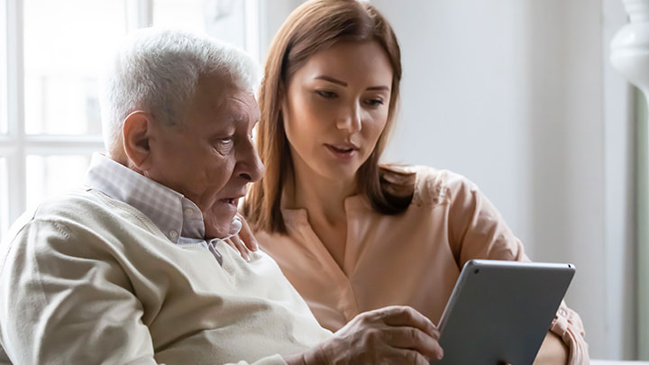 Eine junge Frau und ein &auml;lterer Mann schauen auf ein Tablet
